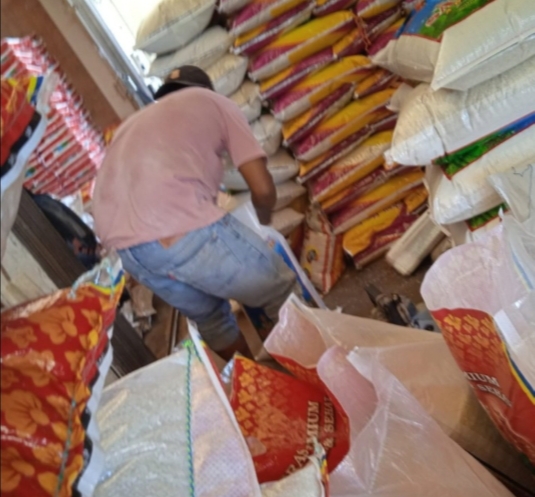 Salah satu pegawai CV.Srijaya saat memindahkan isi beras dari karung Raja Udang ke merk Satelit. Foto: Serunting.id